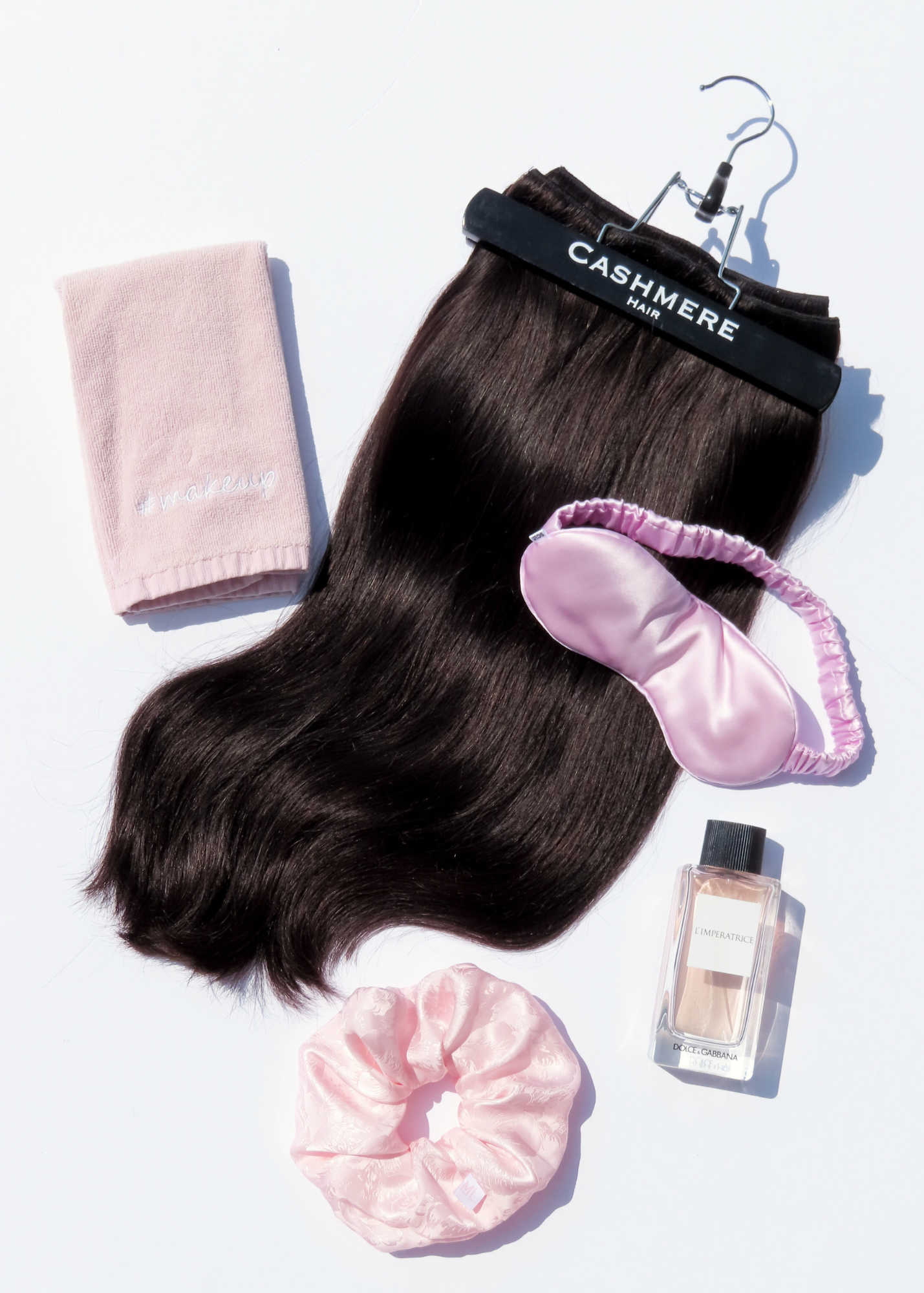 cashmere hair extensions flatlay with sleeping mask, silk scrunchie, perfume and a microfiber towel