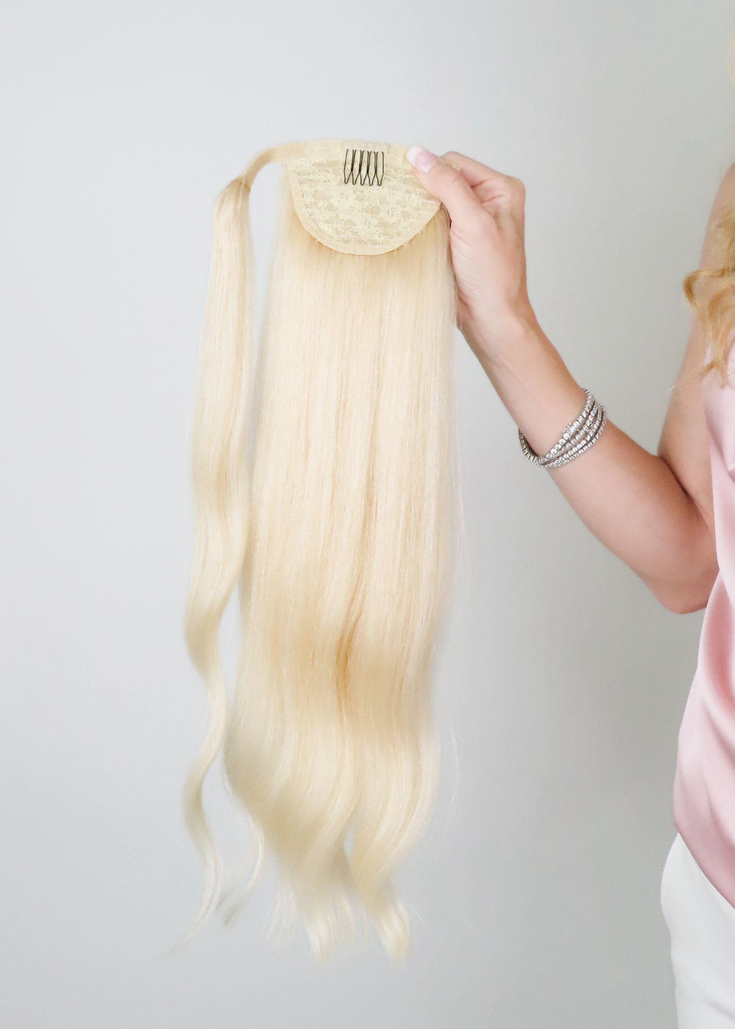 woman holding up a human hair ponytail extension from cashmere hair