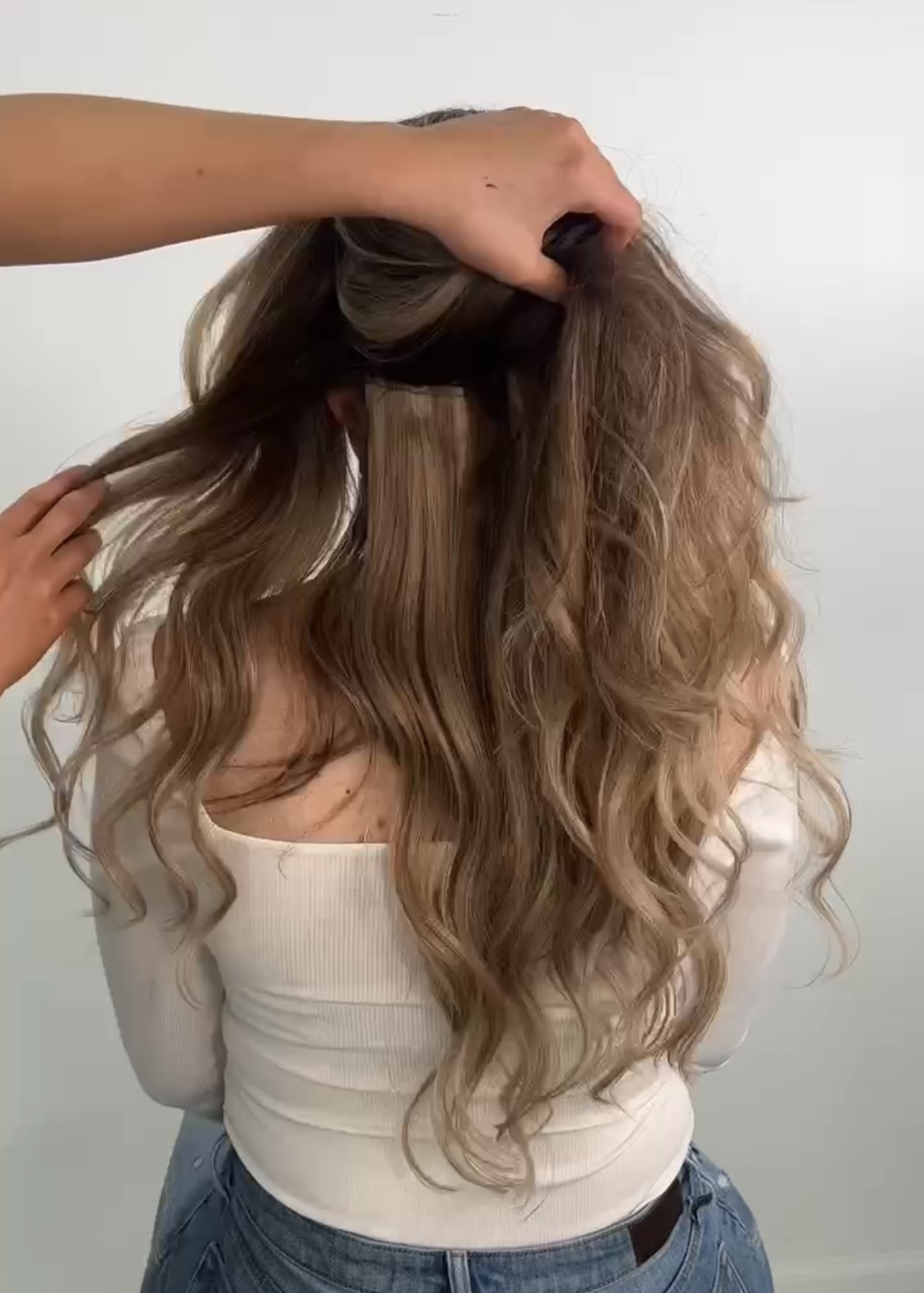 placing seamless clip-ins in the shade Rodeo Drive from Cashmere Hair onto woman