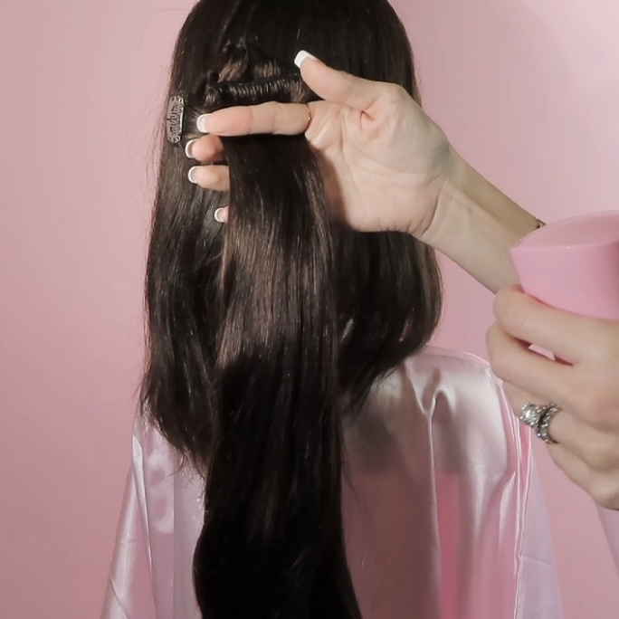 spraying cashmere hair clip in extensions with pink spray bottle