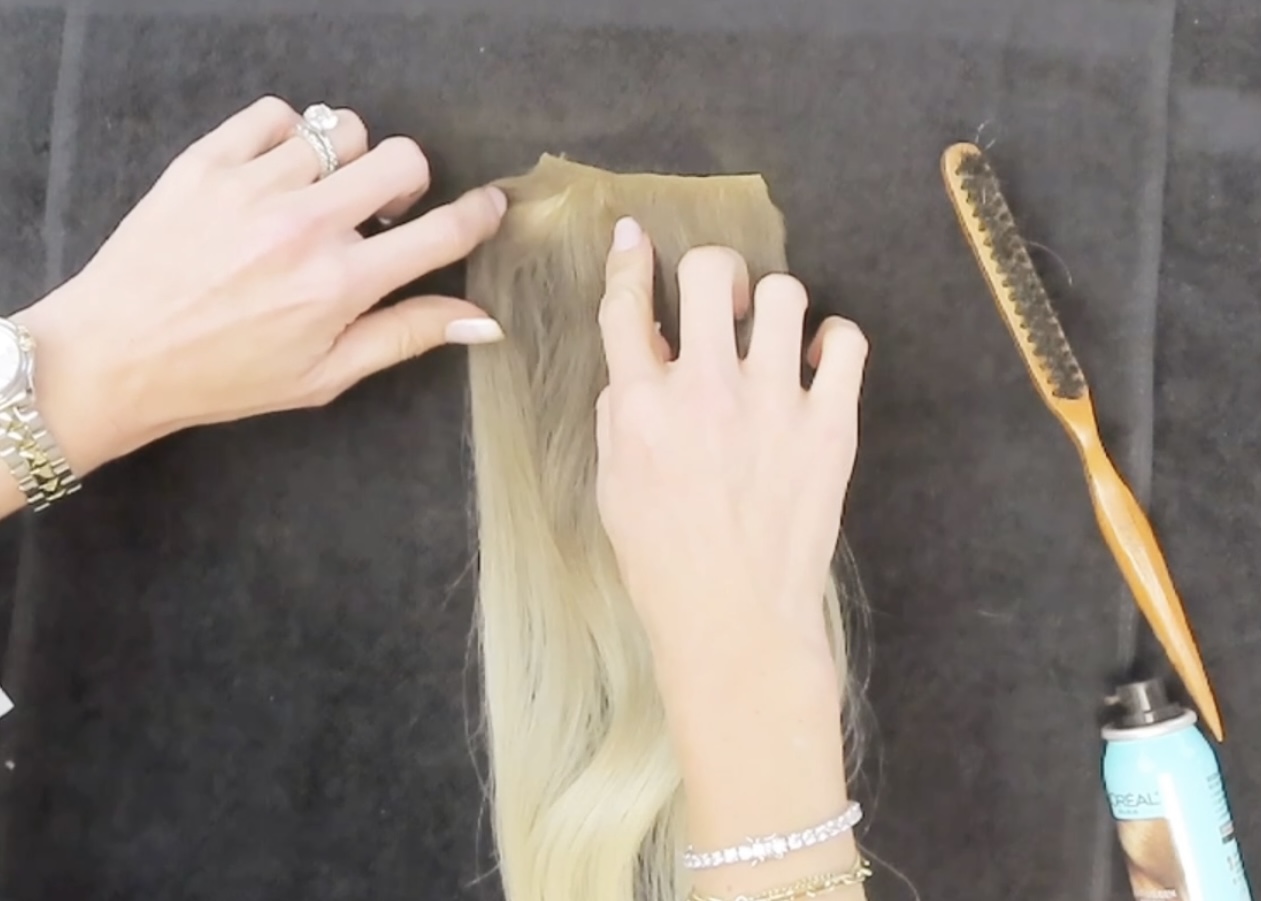 separating hair extensions in between to spray with root spray