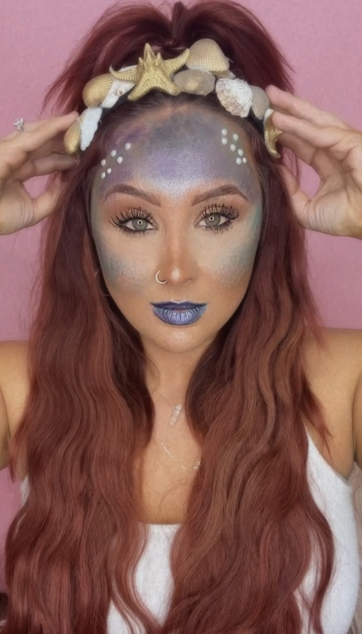 girl in mermaid costume putting on shell headband