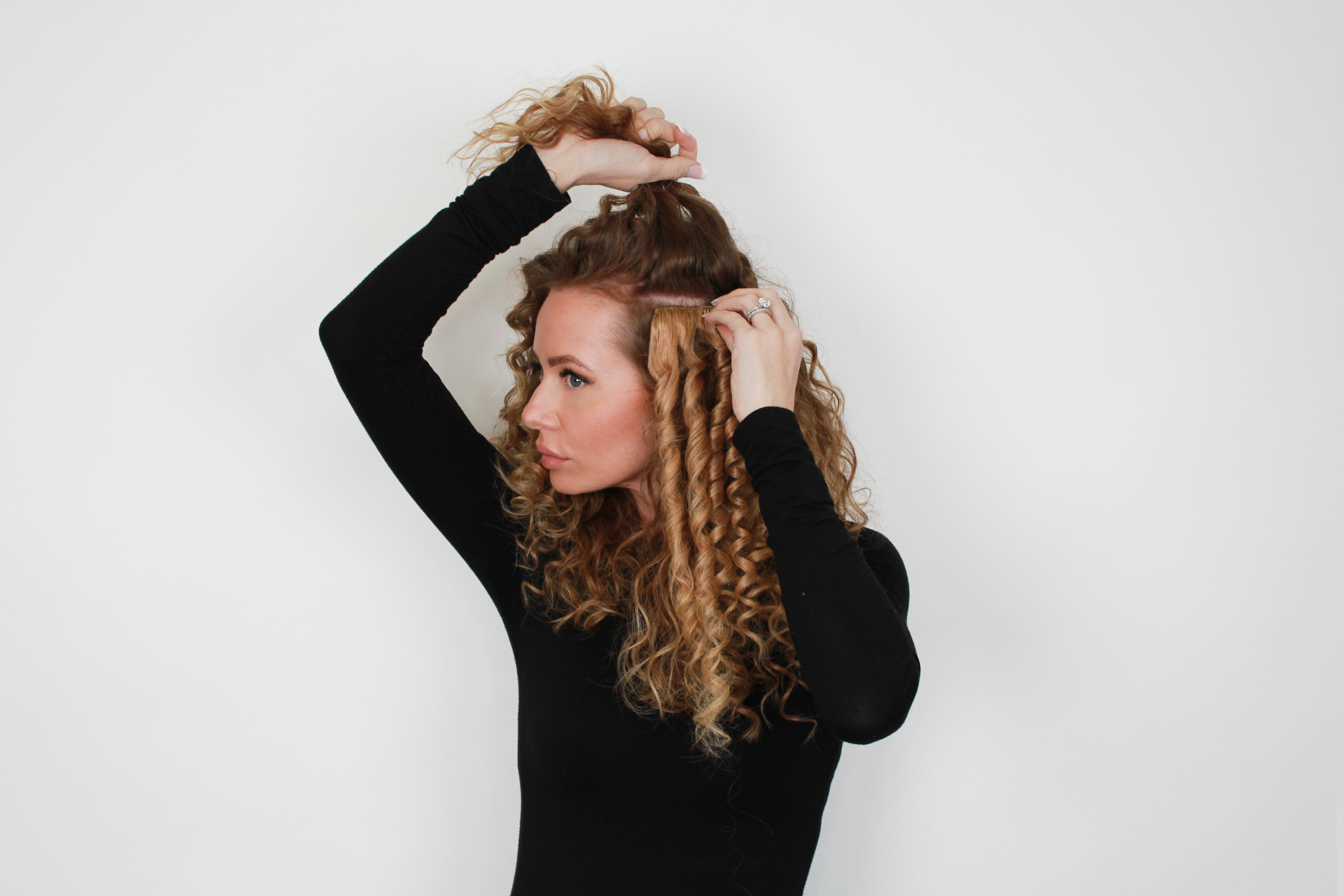 woman clipping in curled side tracks from a classic set hair extensions