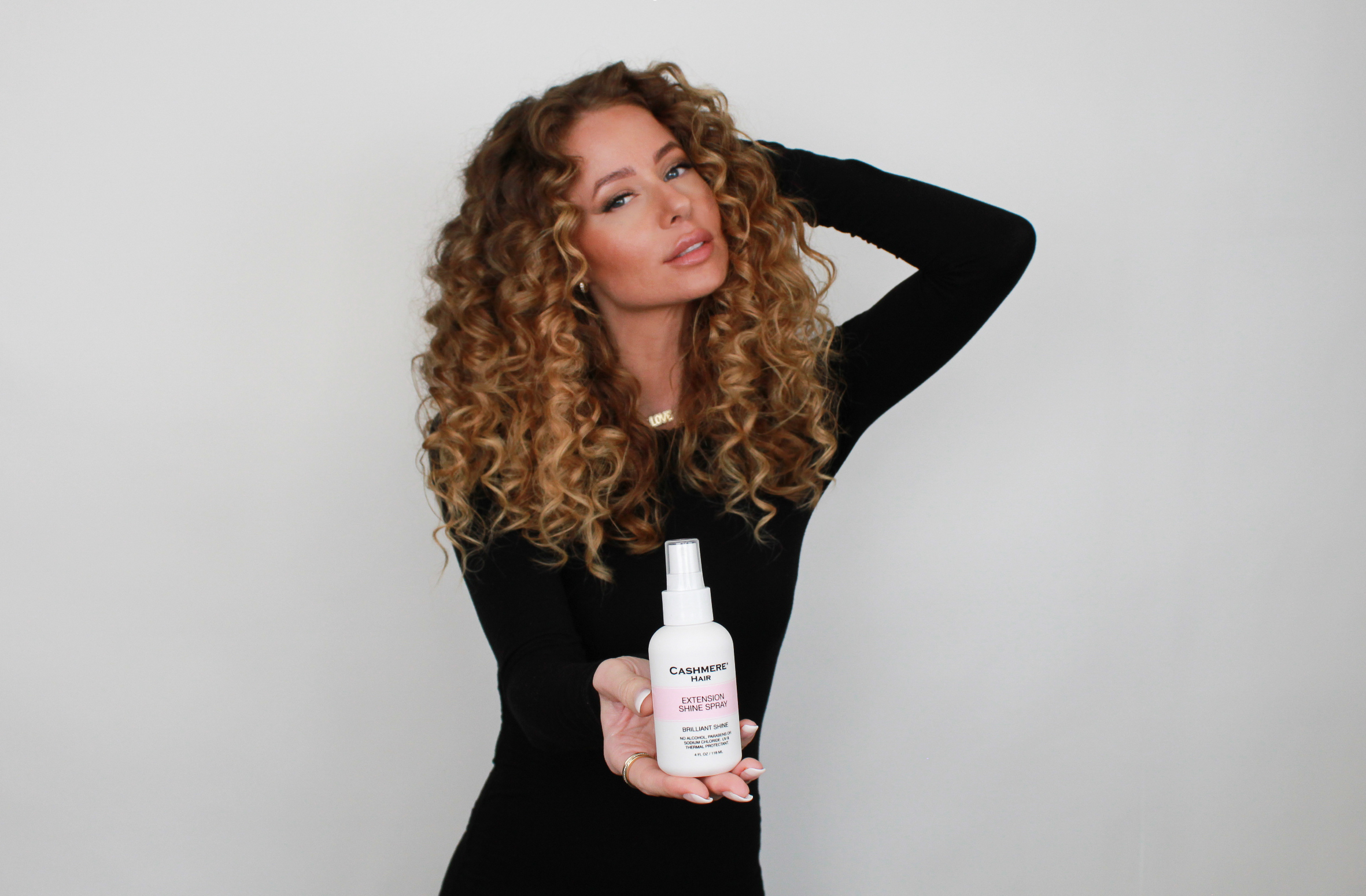 woman holding cashmere hair extension shine spray
