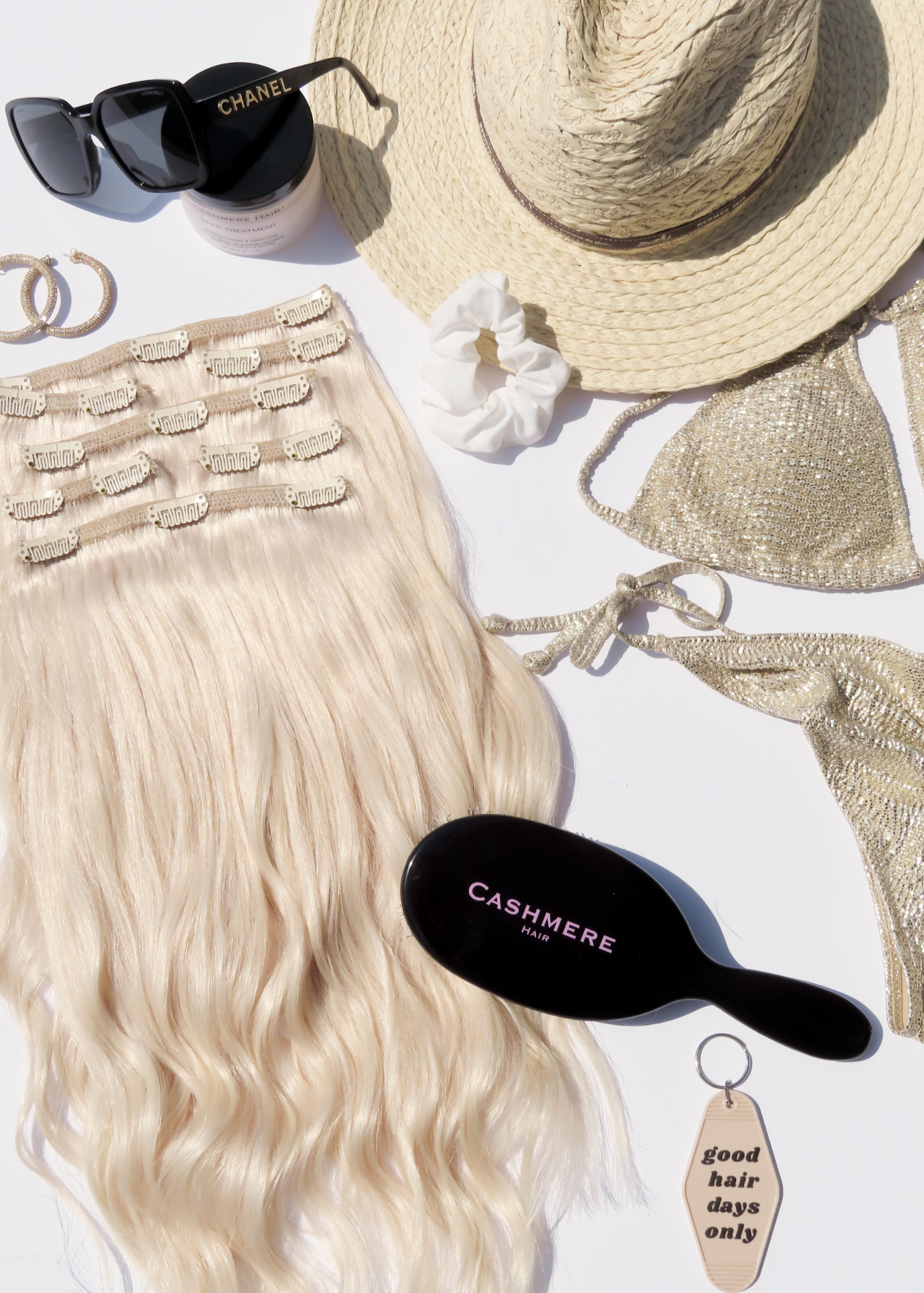 flatlay of cashmere hair seamless extensions with a bikini, sun hat, extension brush and more