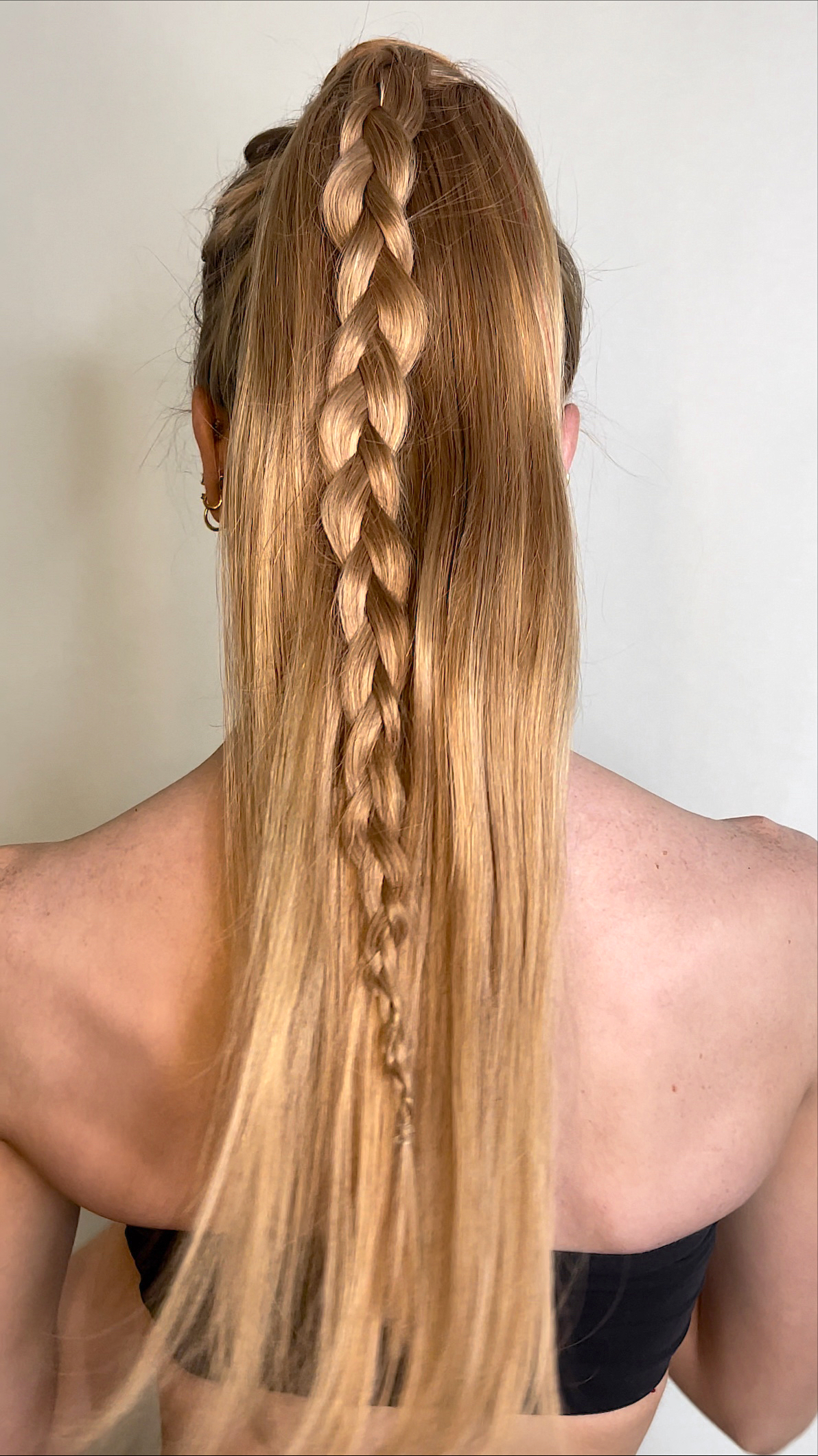 model with strawberry blonde hair in a ponytail with a braid in the center