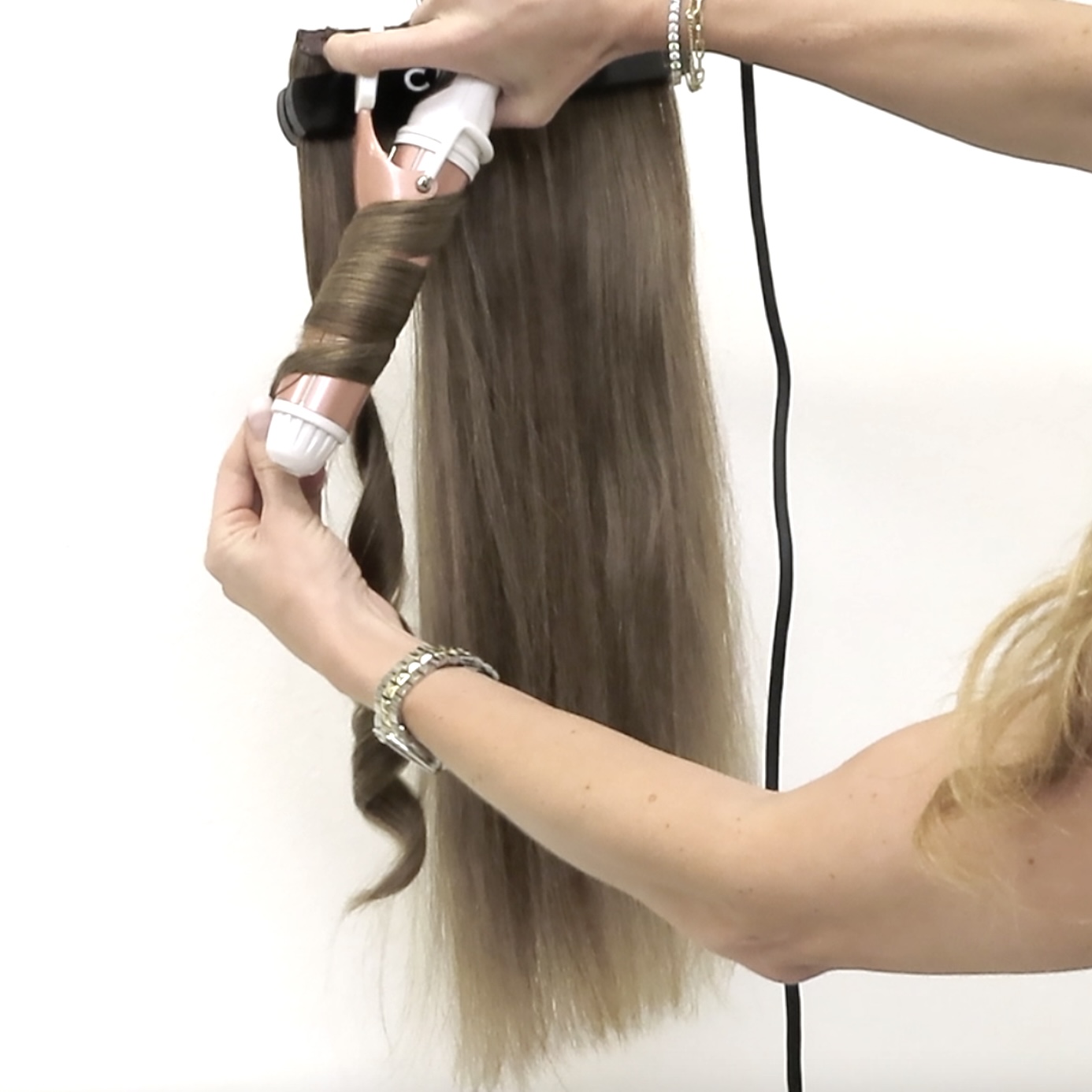 wrapping cashmere hair extensions around a pink curling iron