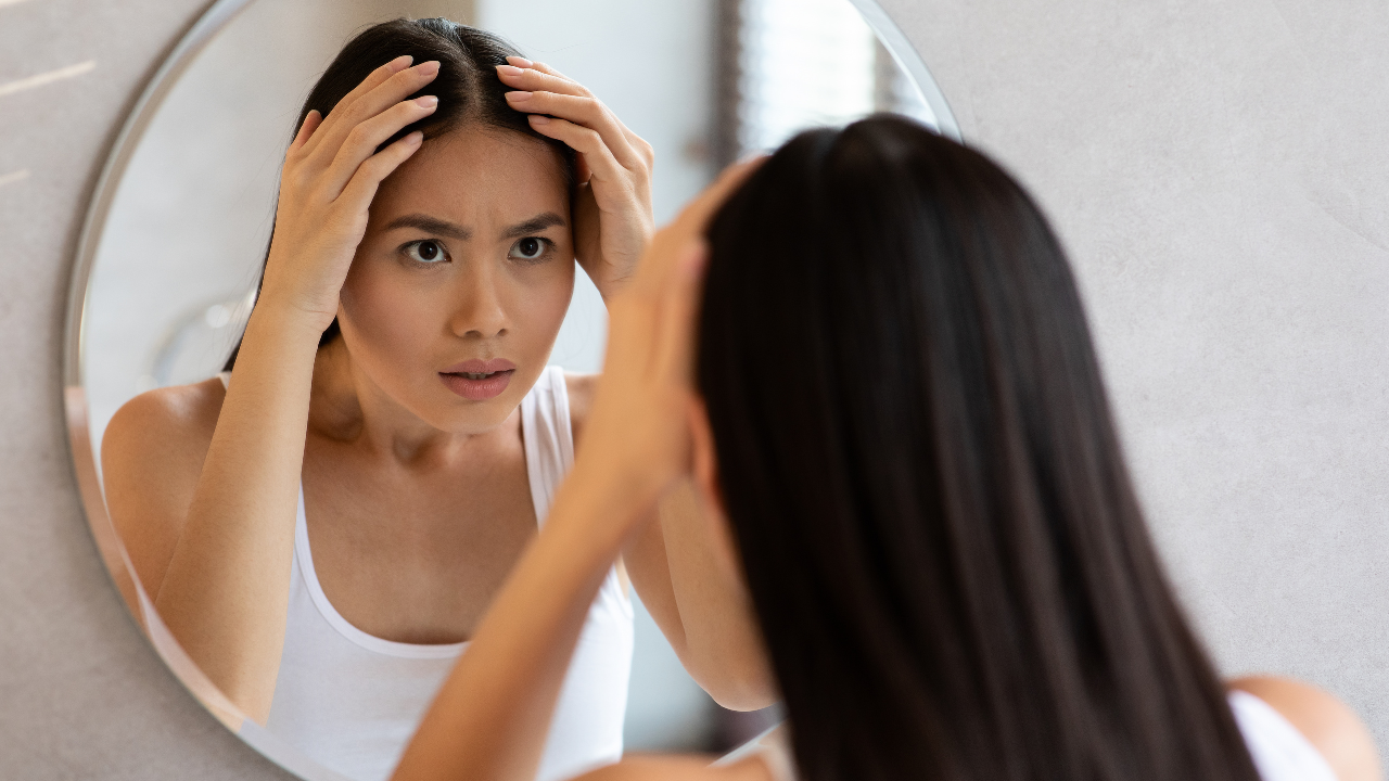 woman looking in the mirror examining her scalp