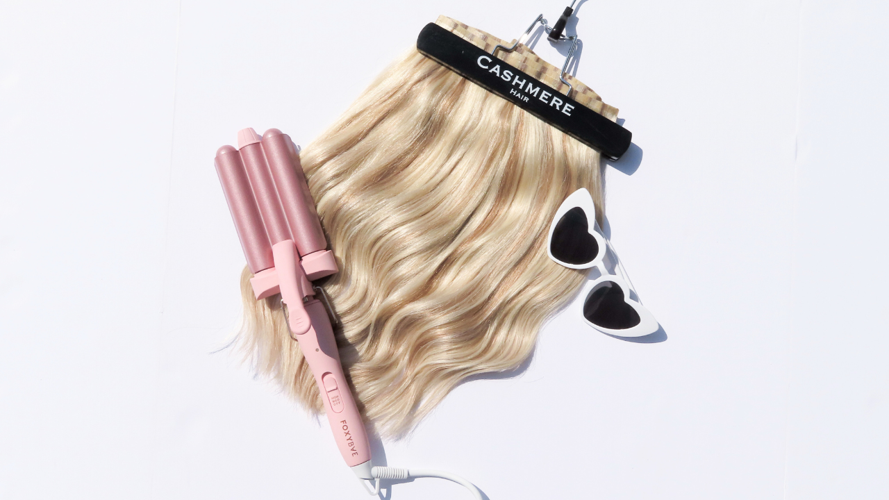 cashmere hair clip-in extensions flatlay with a waver and heart shaped sunglasses